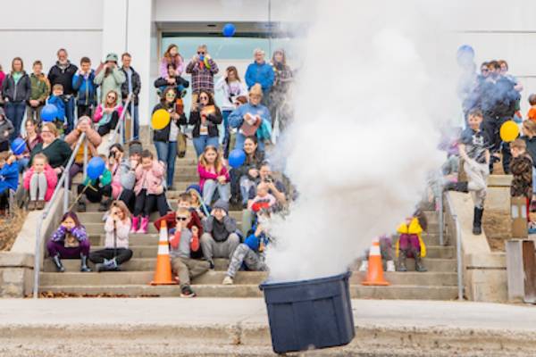 Scientists demontrate a chemical reaction in a puff of smoke outside of a building