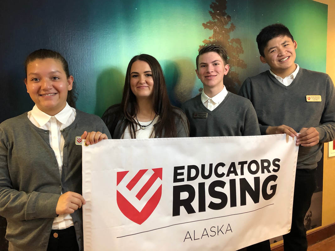 Student members hold up an Educators Rising Alaska banner while posing for a group photo