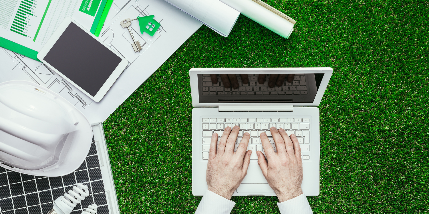 hands typing on a laptop on green grass