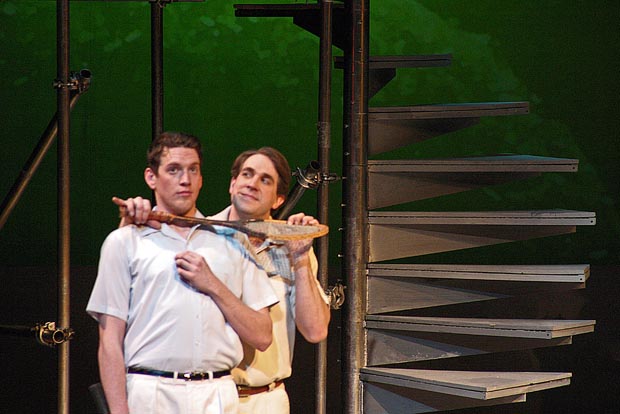 Two men, one behind the other, on stage.