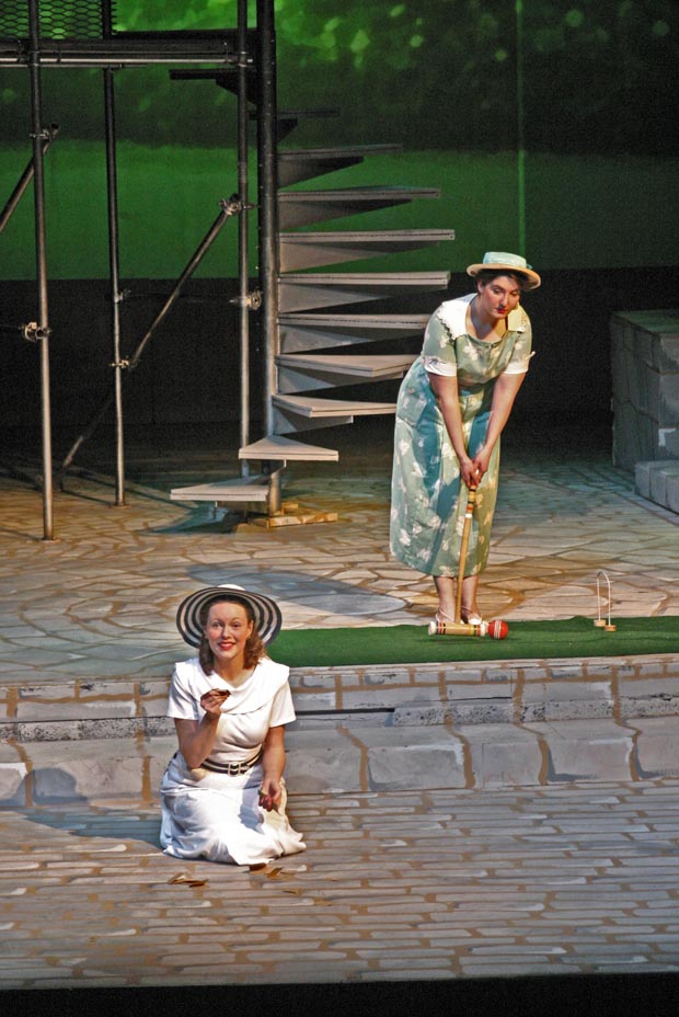 Two women on stage. One kneeling as one is playing croquette.