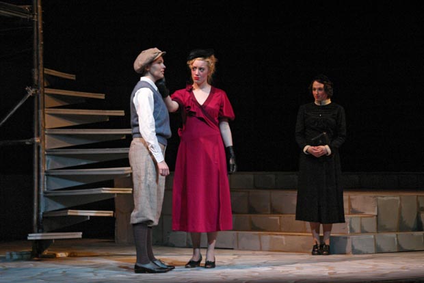 In the spotlight's embrace, a man finds solace in the comforting touch of a woman in red, while another woman, clad in black, observes from a distance, their emotions painting a poignant scene on stage.