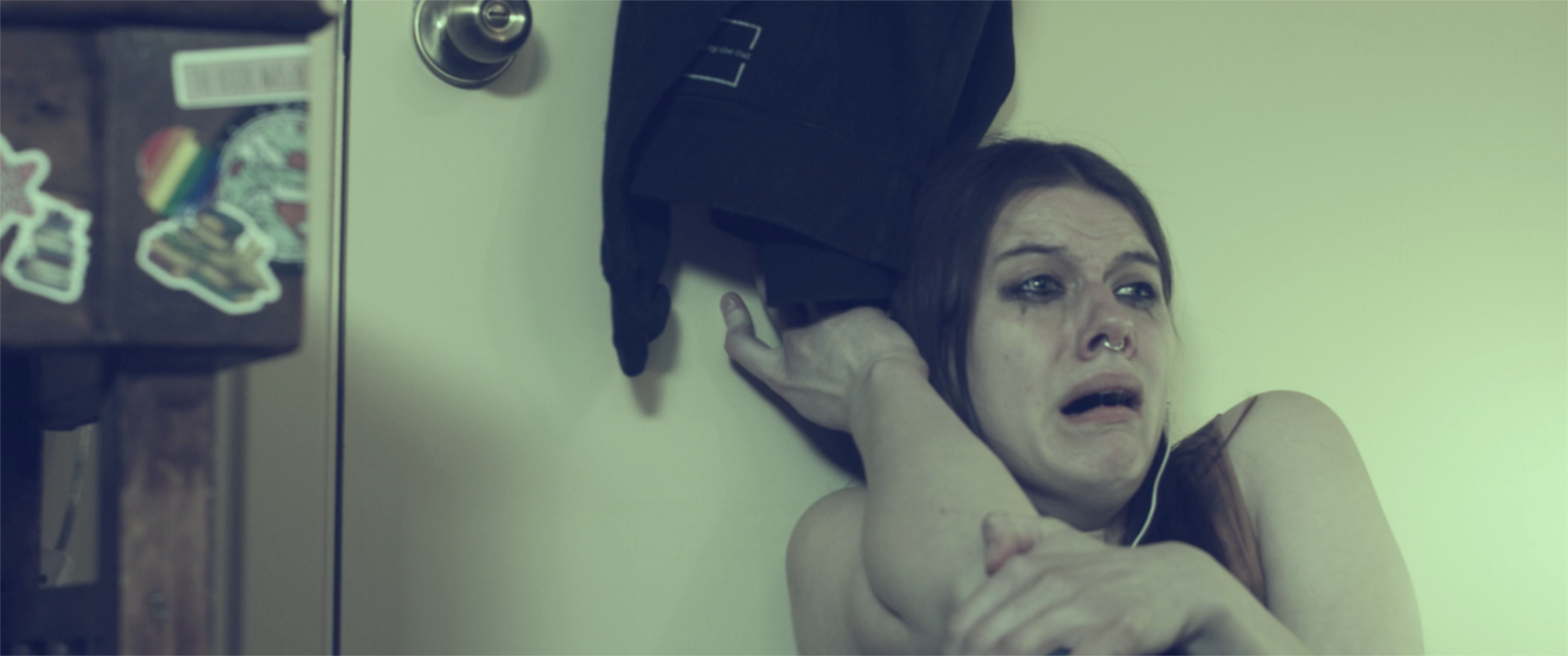 Jessica Wohlwend as Riley stars in the film production of MEND. Riley shelters in her room against the door, fearful of what is on the other side. Production still from 'Mend' a short film by JB Brown