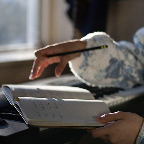 Julieth Harvey's hand paused hovering over an open notebook. Photo credit: Eric Marshall