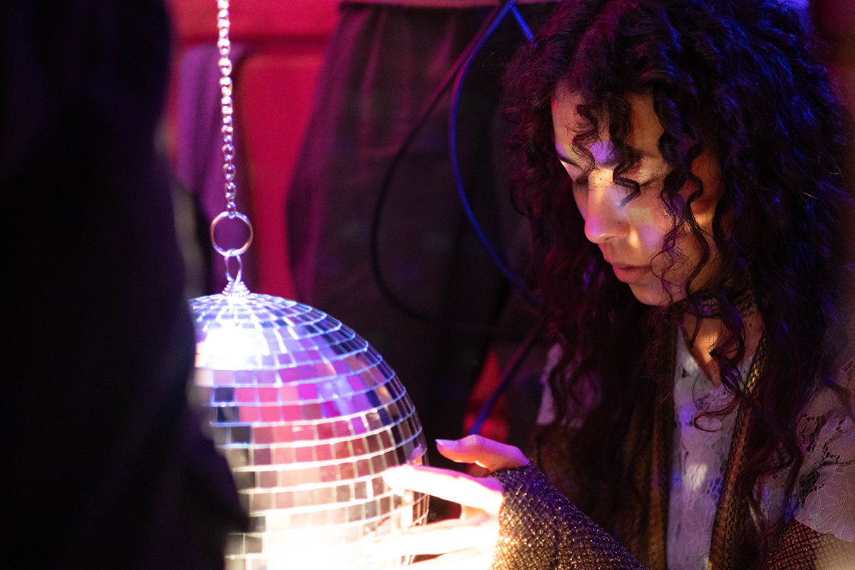 TAOS, Day 4, image 135 Julieth Harvey looks into the mirrored surface of a disco ball during the filming of The Anatomy of Sound. Photo credit: Eric Marshall