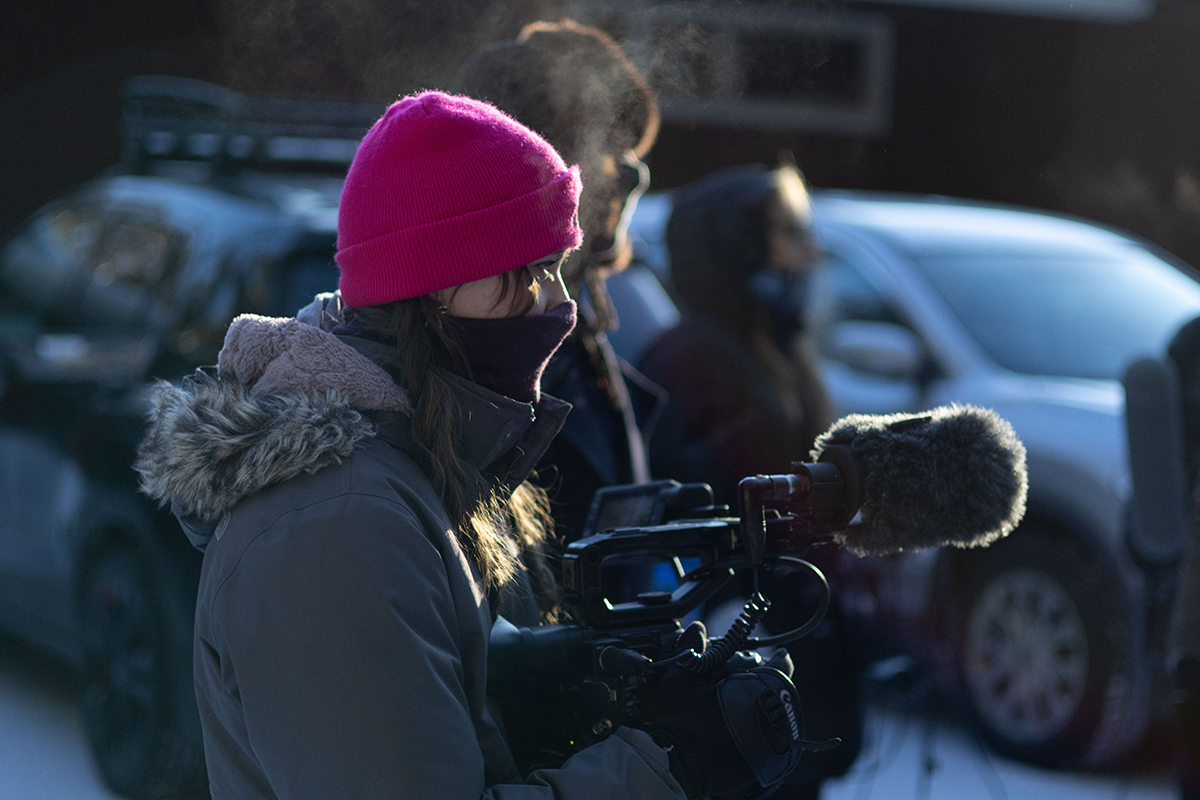 TAOS, Day 4, image 43 A crew member bundled in a coat, hat and scarf points their camera at the action on set of The Anatomy of Sound. Photo credit: Eric Marshall