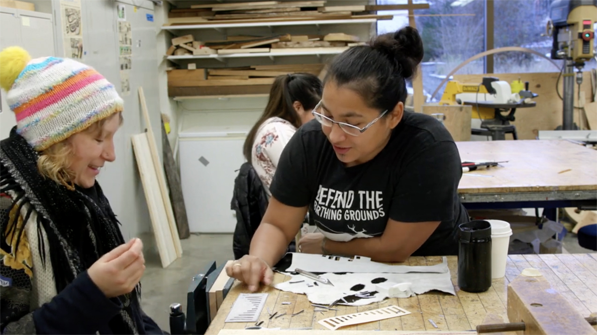 To Continue or Be Remembered Artist Marjorie Tahbone helps a students stitch calf skins. Still from To Continue or Be Remembered