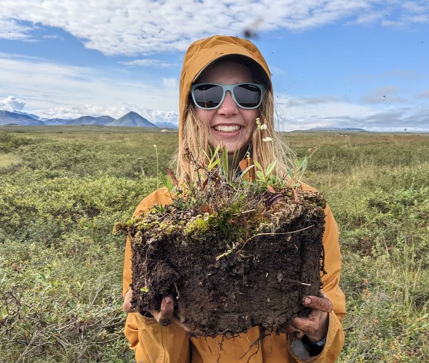 Research assistant holding a monolith of tundra