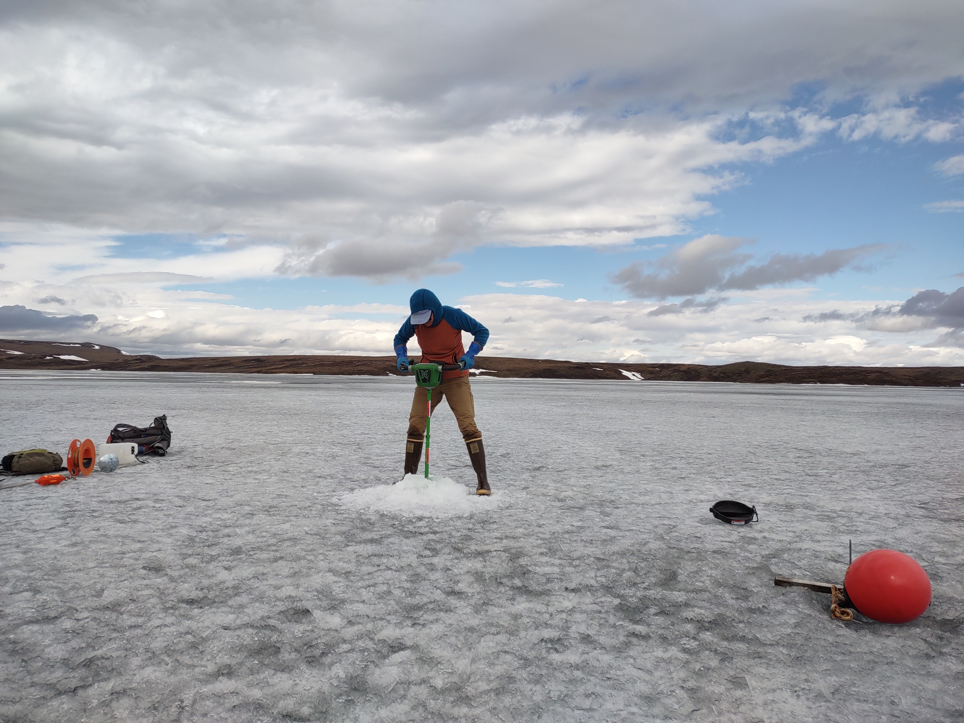 a person drills into lake ice using an auger