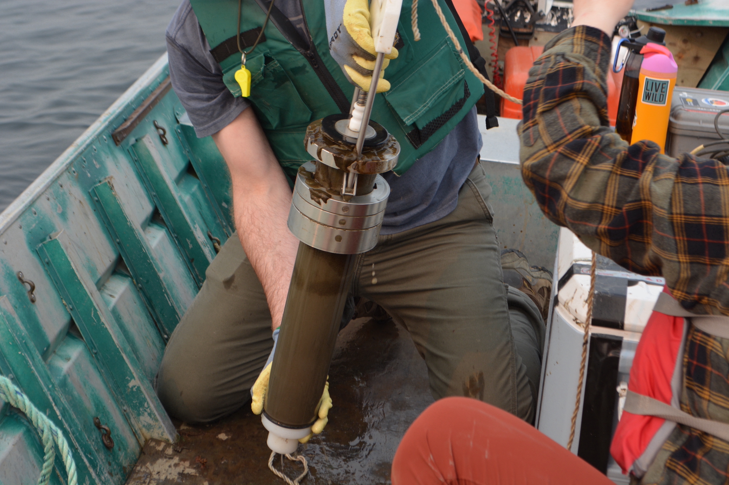two people pulling a sediment core up onto a boat