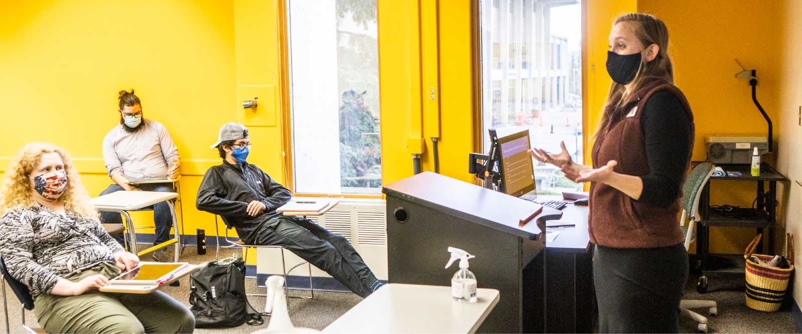 A masked instructor addresses masked and physically distanced students in a UAF classroom