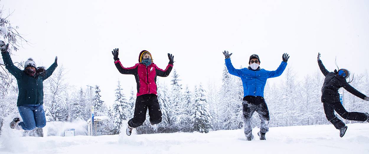 Students wearing masks and jumping in the snow