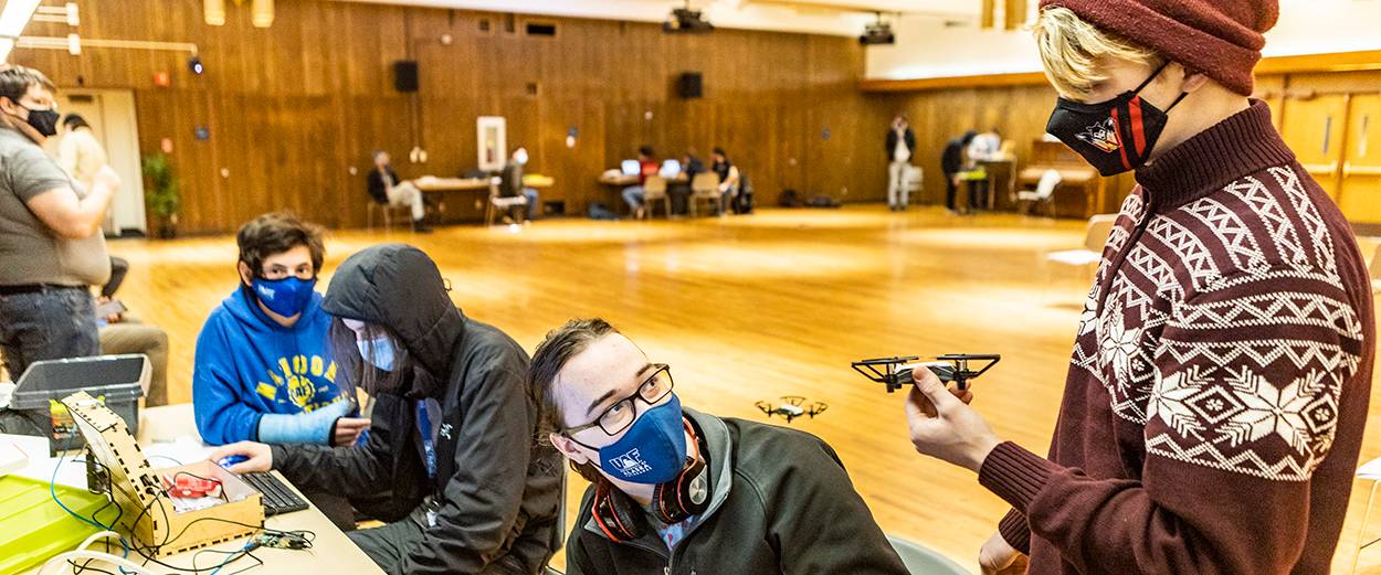 Students wearing masks in the Wood Center ballroom. One holds a drone.