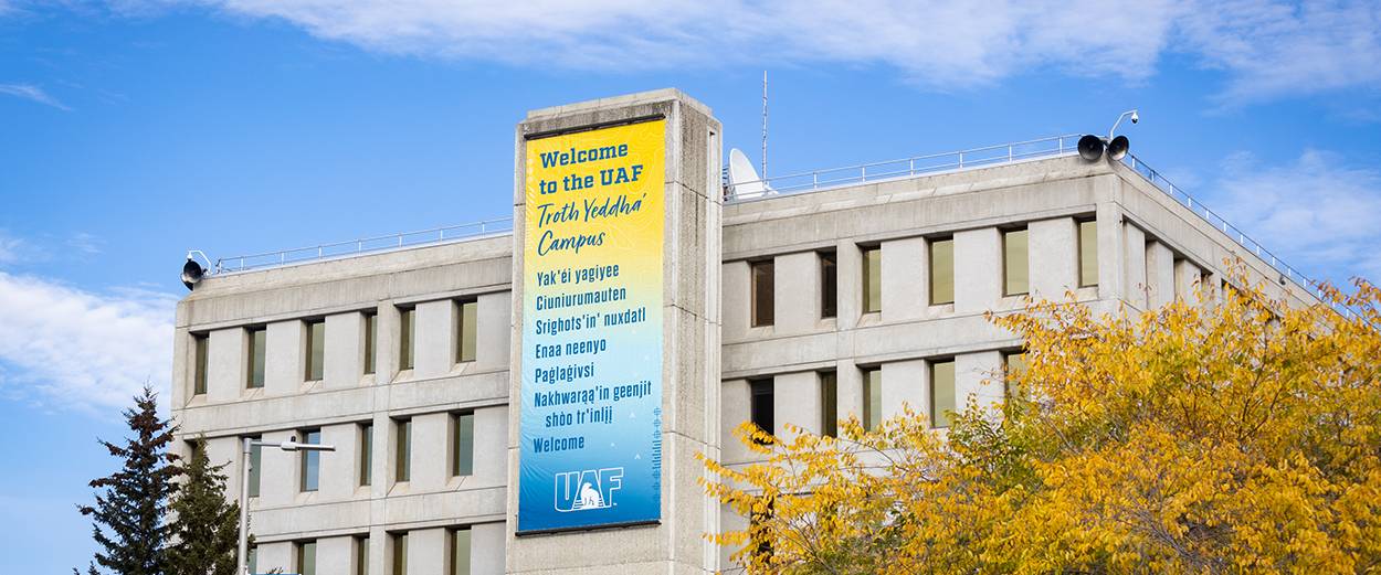 A banner hanging from the Gruening Building welcomes visitors to campus in English and in six different Alaska Native languages.