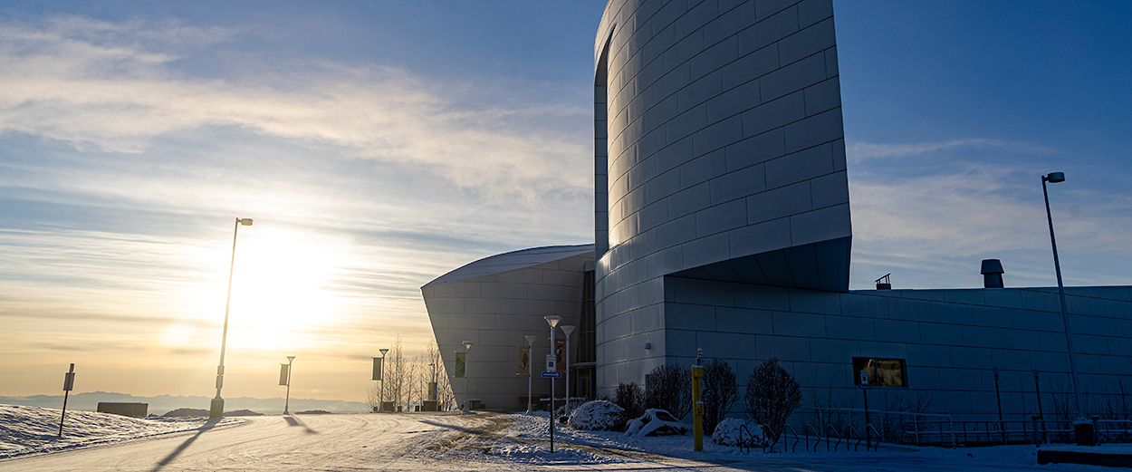The sun sets over the west ridge of the Troth  Yeddha' campus in Fairbanks. The UA Museum of the North is in the foreground.