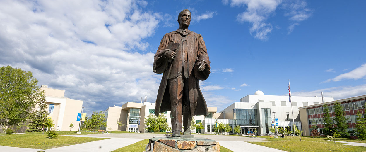 Bunnell statue on a summer day with Cornerstone Plaza, Brooks, Duckering, Usibelli and Bunnell buildings in the background