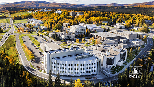 An aerial west-facing view of the Fairbanks campus in autumn with the UAF logo in the lower right corner.