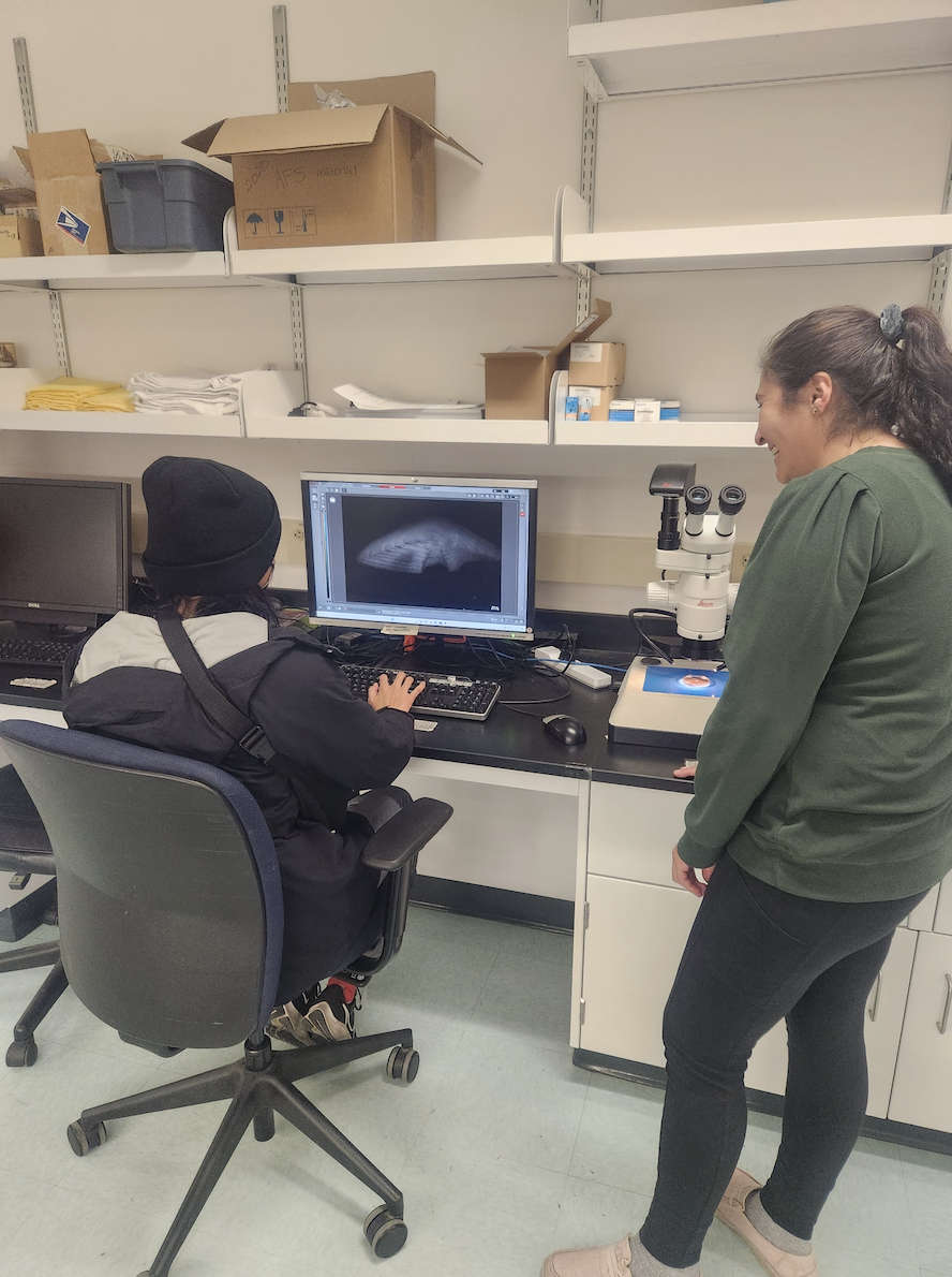 Nivedita Menon (left) and Anna Medina (right) view an otolith under a microscope.
