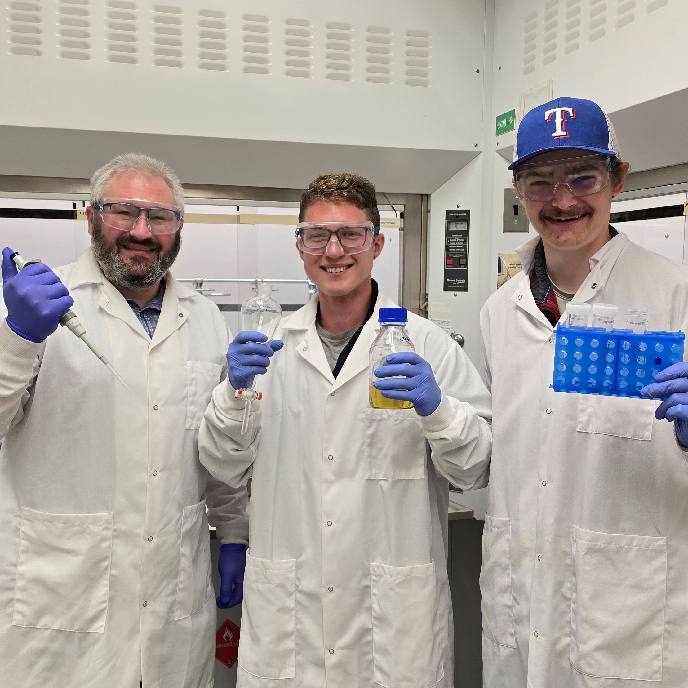 Florian, Lee and Alex are in labcoats and gloves in the lab.