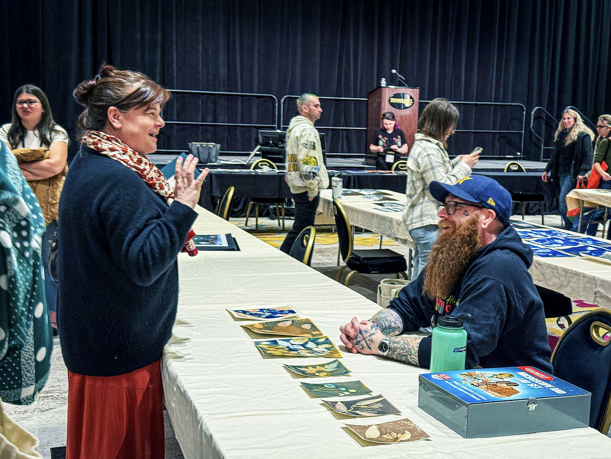 David sits at a table showing his artwork